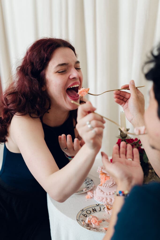 Couple laughing while feeding each other cake during vintage Valentine’s Day mini session at LA Loft Studios in Los Angeles.