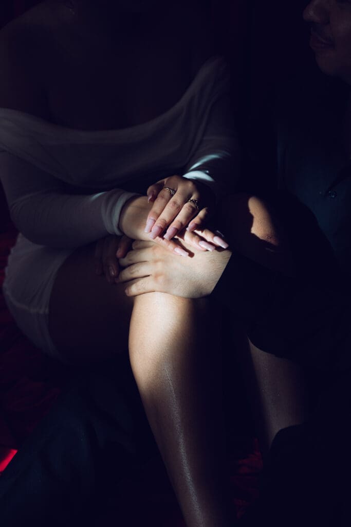 Romantic close-up of couple’s hands resting together in soft spotlight lighting during vintage Valentine’s mini session in Los Angeles studio.