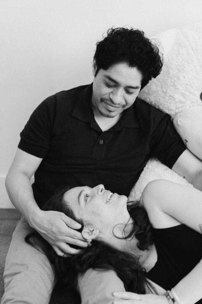 Black and white portrait of woman resting across partner’s lap surrounded by oversized teddy bears during romantic Valentine’s Day mini session at LA Loft Studios in Los Angeles.