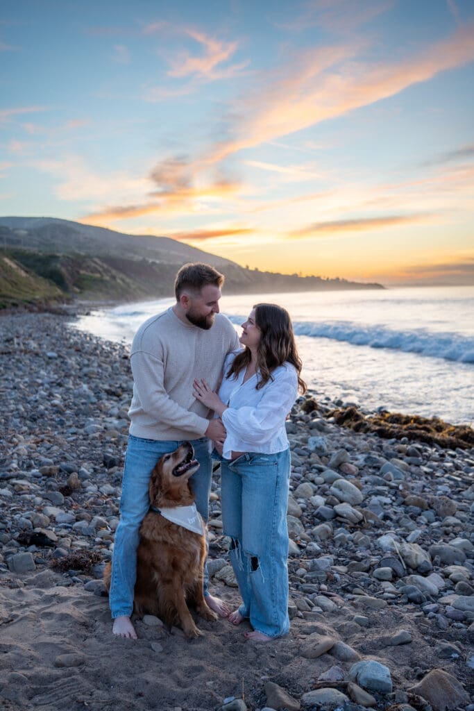 Expectant couple with their golden retriever during a sunrise maternity session at Leo Carrillo State Beach in Malibu, California.