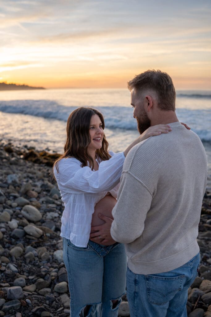 Expectant parents embracing during a sunrise maternity photography session at Leo Carrillo State Beach.