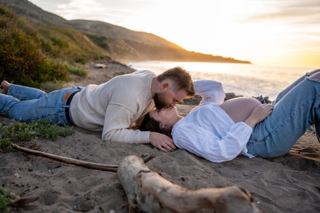 Parents-to-be sharing a quiet moment together at sunrise during an outdoor maternity session at Leo Carrillo State Beach.