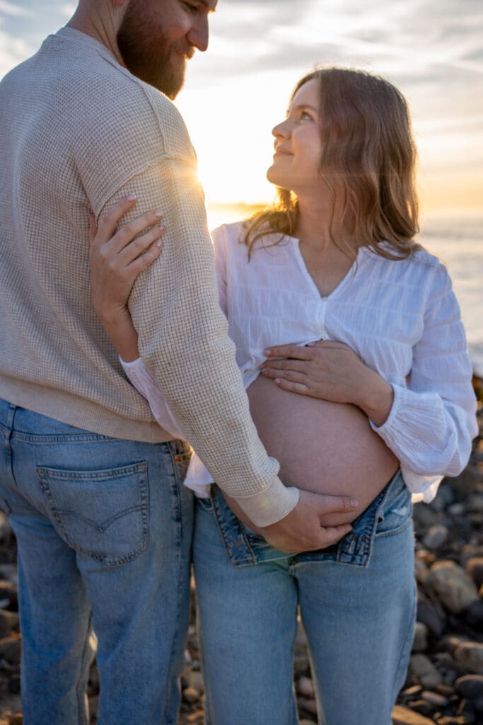 Expectant couple sharing a quiet moment during a sunrise maternity session at Leo Carrillo State Beach.