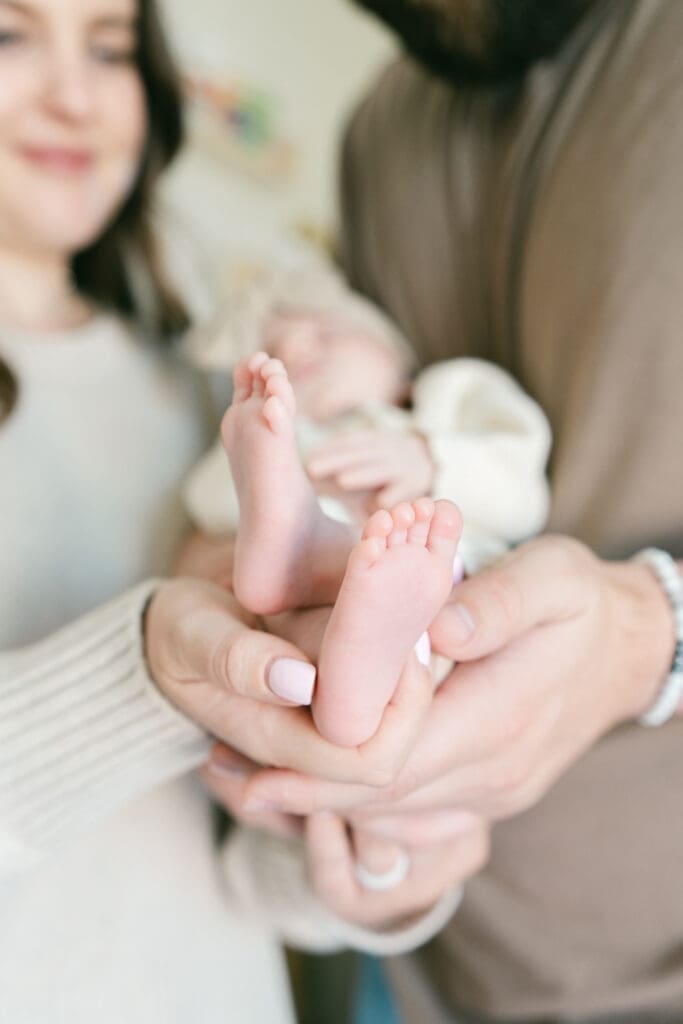 Close-up of a newborn's tiny feet held by her parents during an in-home lifestyle newborn photography session in Camarillo, California.