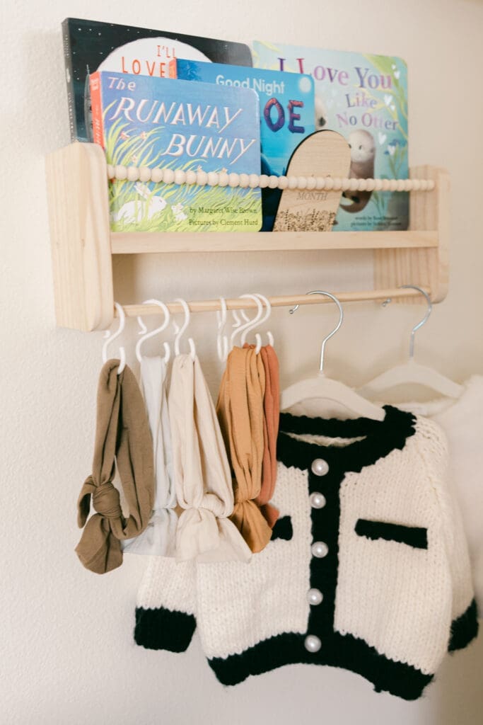 Nursery details featuring children's books and baby clothing during an in-home newborn session in Camarillo.