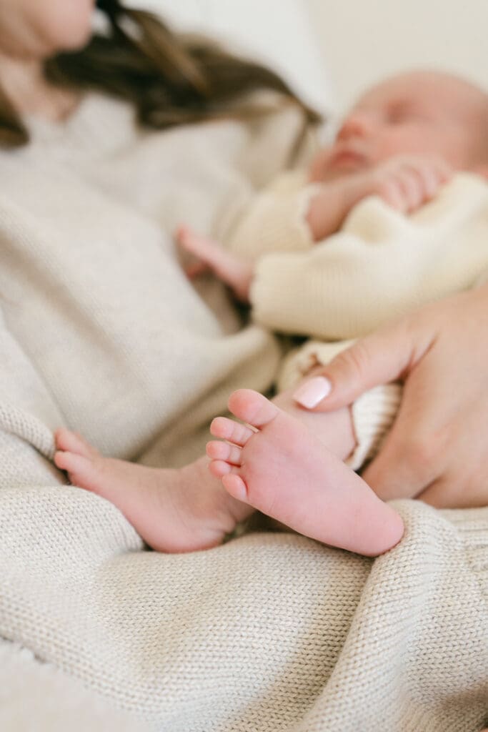Close-up of a newborn's tiny feet while being cuddled during an in-home lifestyle newborn photography session.